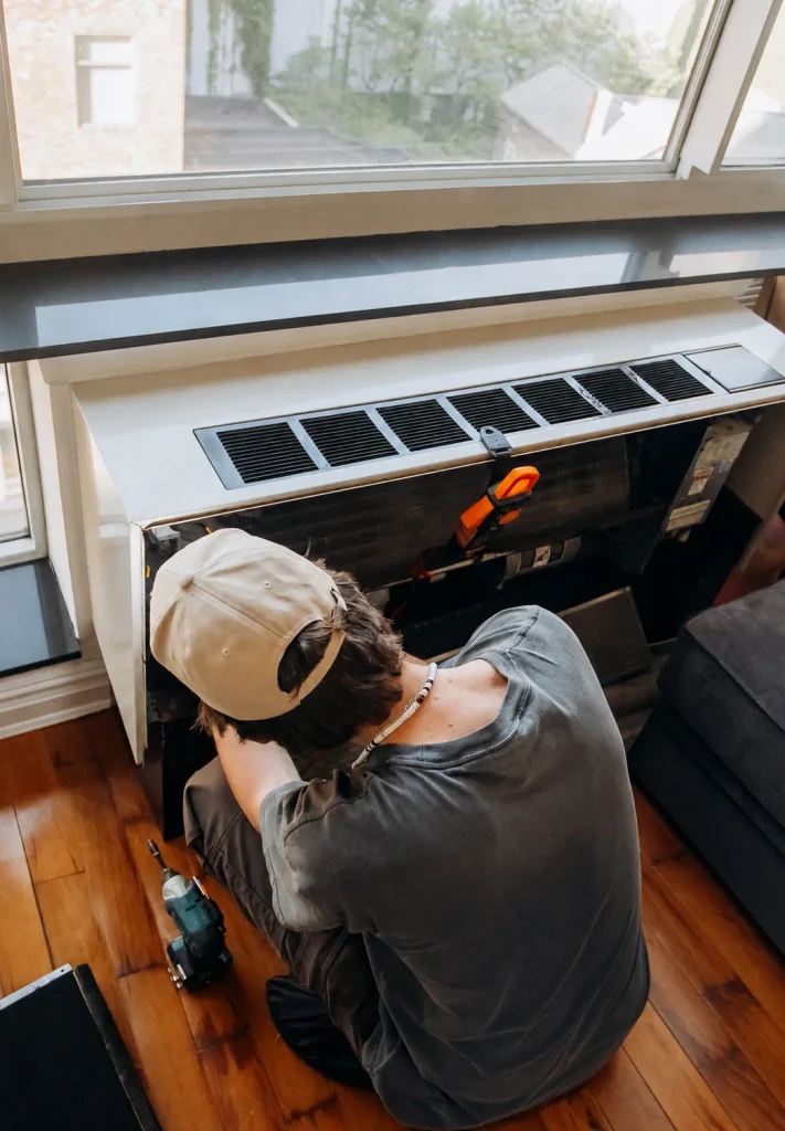 HVAC technician servicing a PTAC unit installed in a wall sleeve